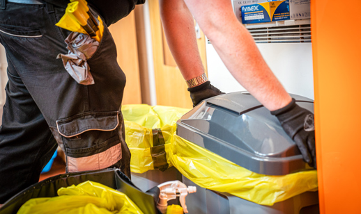 phs technician servicing a sanitary bin in a washroom cubicle