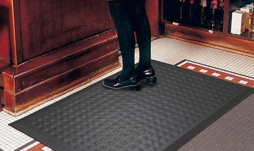 Lady standing on an anti fatigue mat in front of a desk