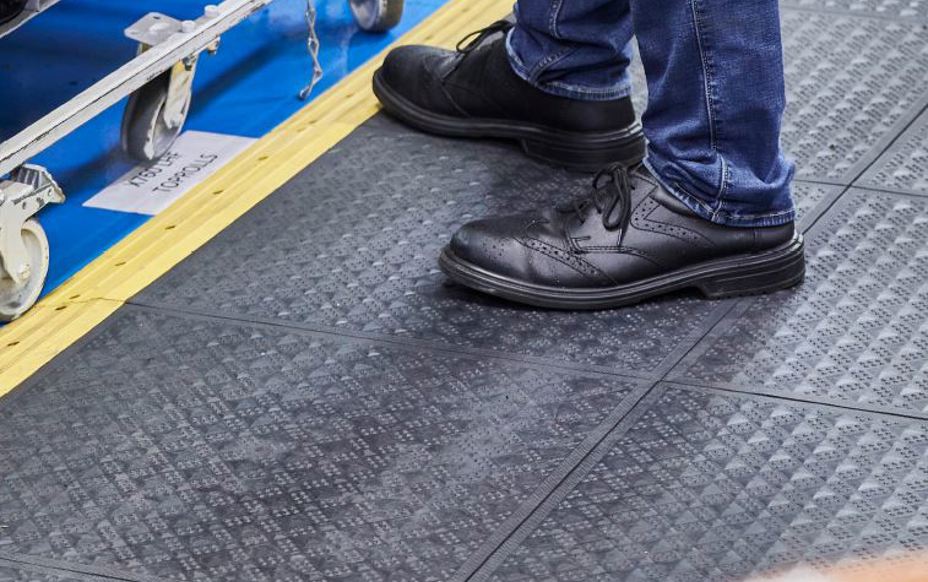 Man standing on an anti fatigue mat within an industrial workplace