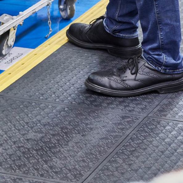 Man standing on an anti fatigue mat within an industrial workplace