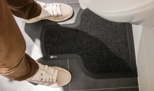 Person using urinal, with urinal mat placed on floor