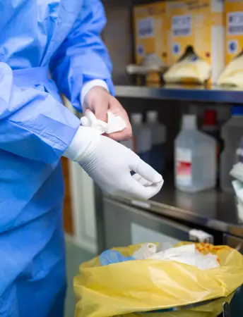 Surgeon removing gloves and putting them into a offensive waste bag